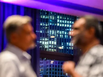 Two Richard von Weizsäcker Fellows discussing and blurred in the foreground. In the background is a high-rise building at night. 